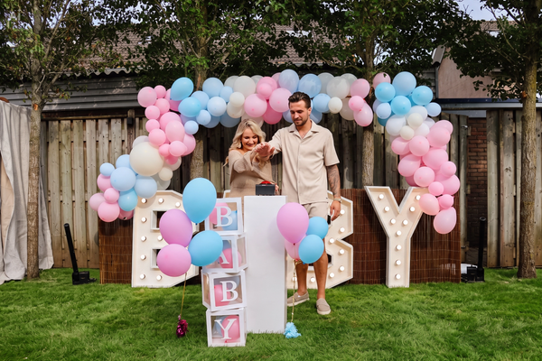 Gender reveal opstelling met vier statafels met roze rok, BABY-lichtletters en witte stoelen