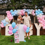 Gender reveal opstelling met vier statafels met roze rok, BABY-lichtletters en witte stoelen